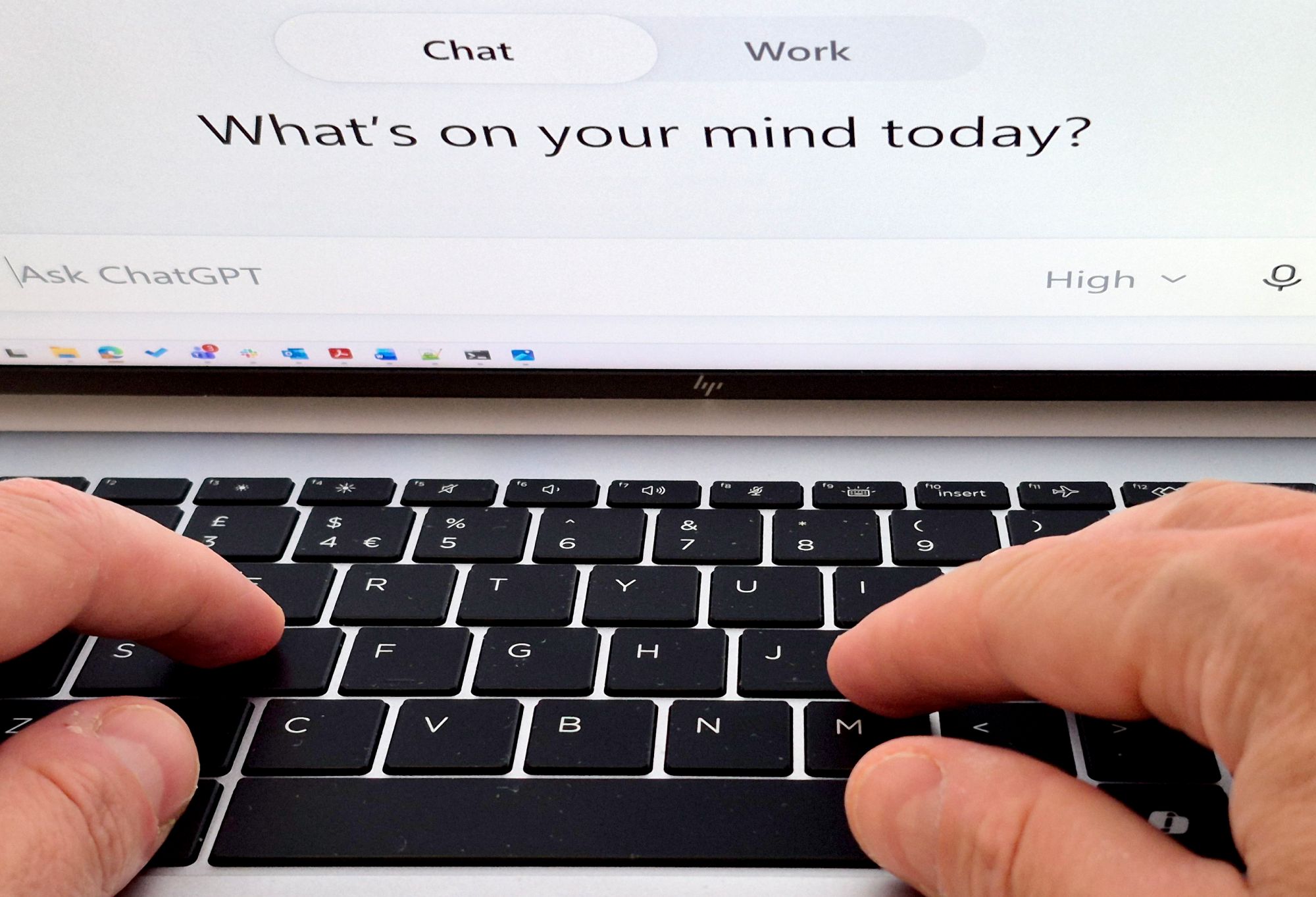 A laptop keyboard, hands and ChatGPT.
